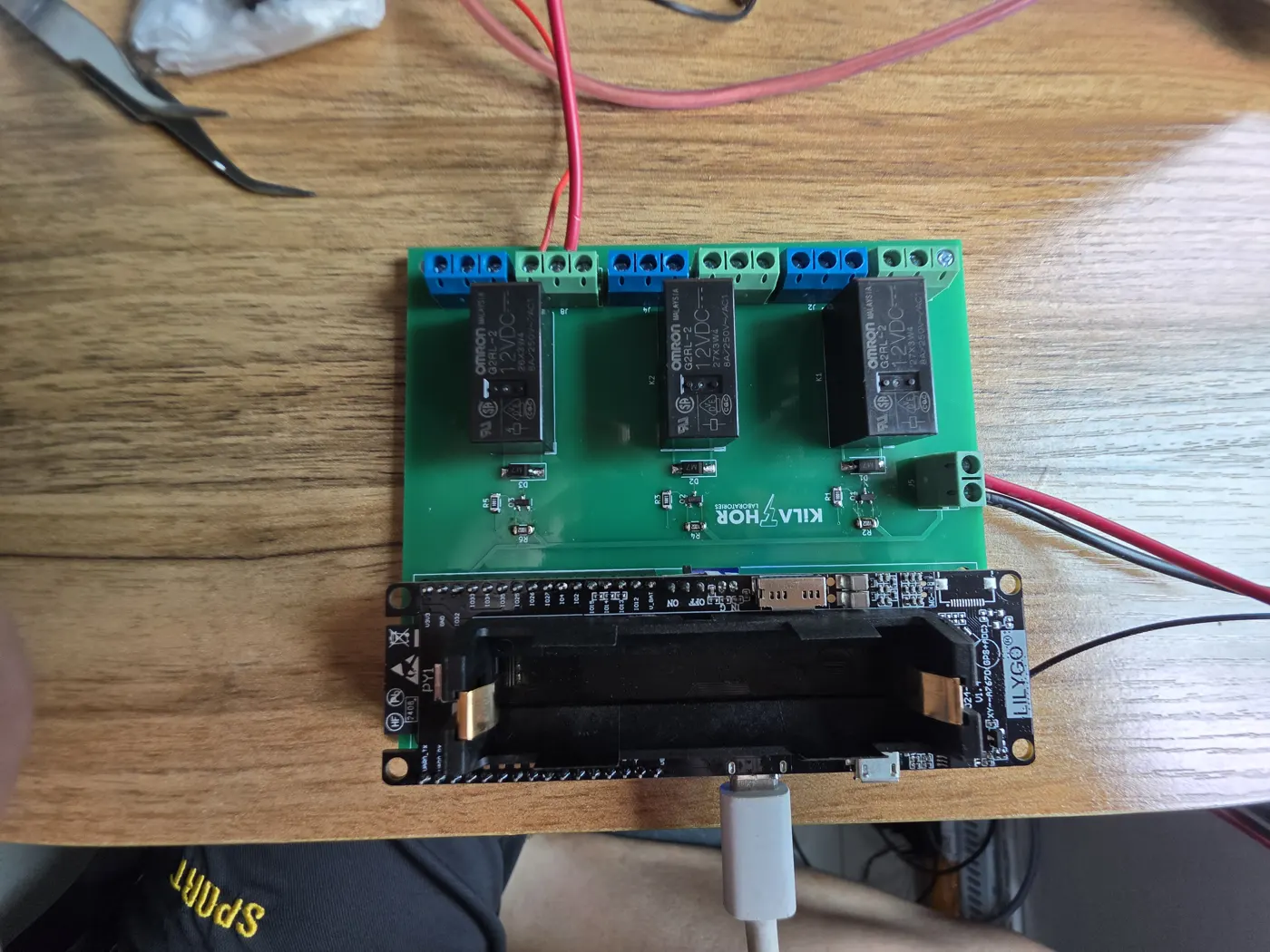Green KiLATHOR relay board with three relays and an ESP32 module, on a workbench