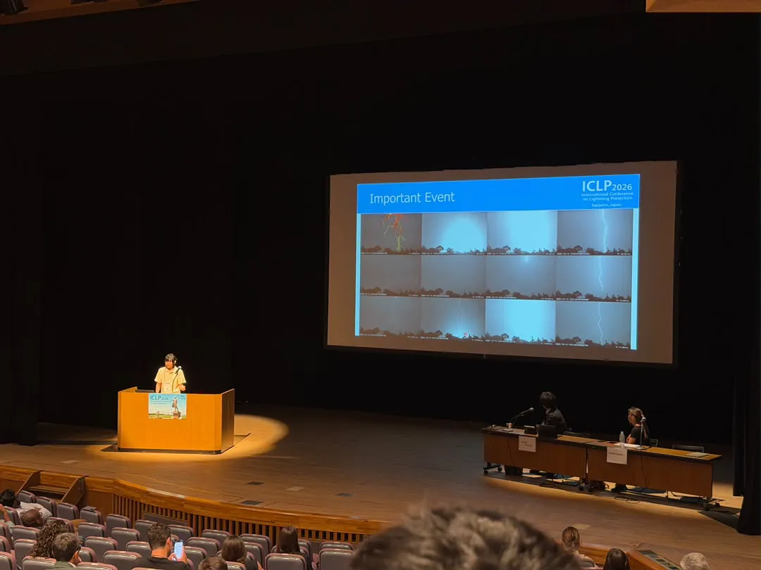 Zahin at the podium of ICLP 2026 in Sapporo, with high-speed lightning frames on the big screen