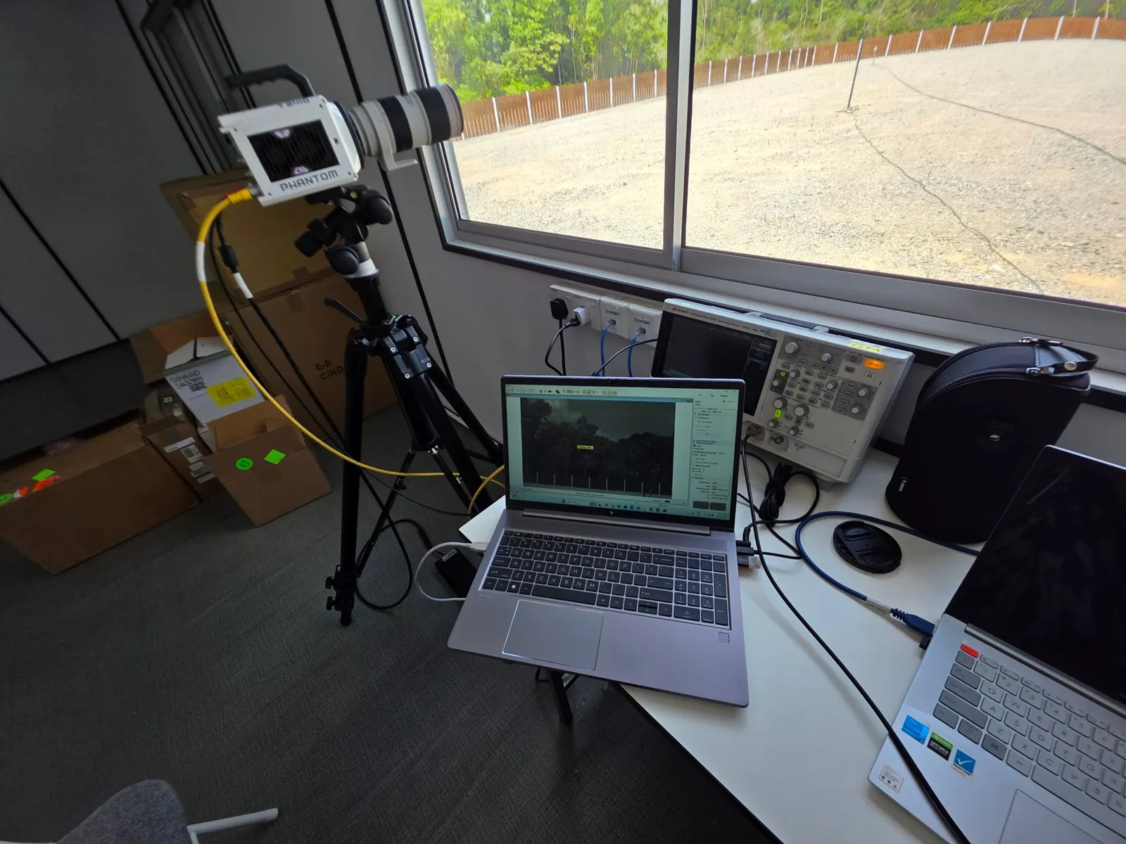 A Phantom high-speed camera on a tripod by the window, aimed at the launch field, with a laptop and oscilloscope