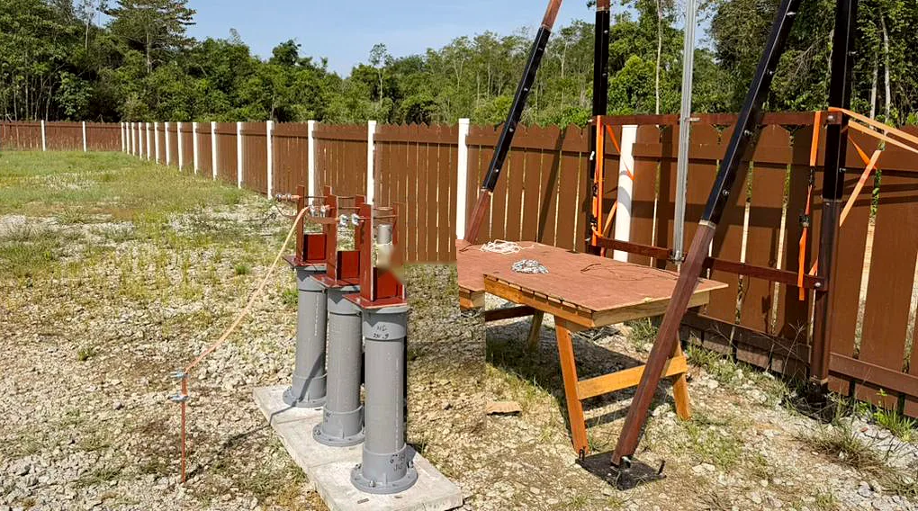 Three rocket launch tubes on concrete pads at the triggered-lightning field site, next to a work table