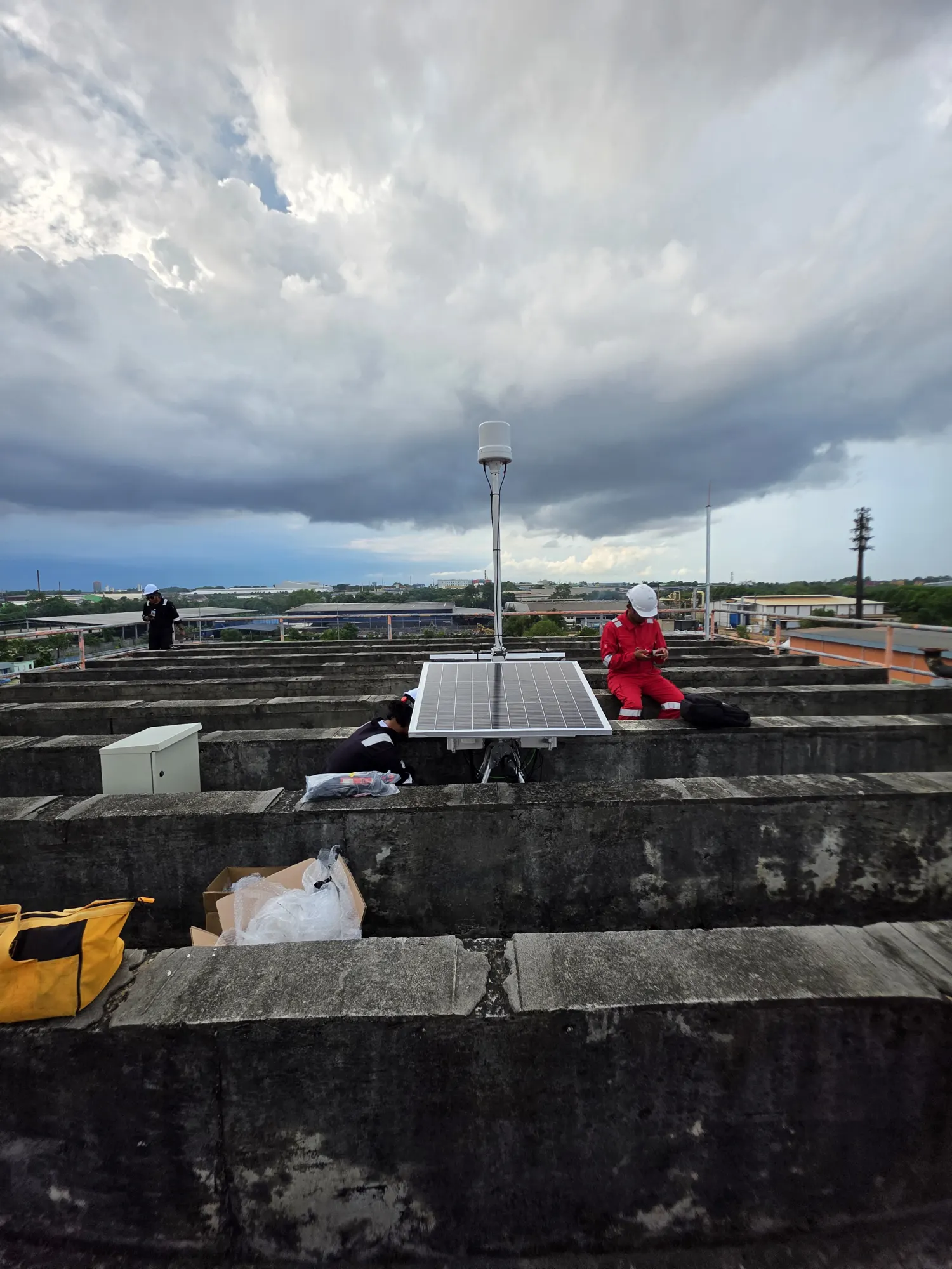 A solar-powered sensor station on a rooftop under heavy storm clouds