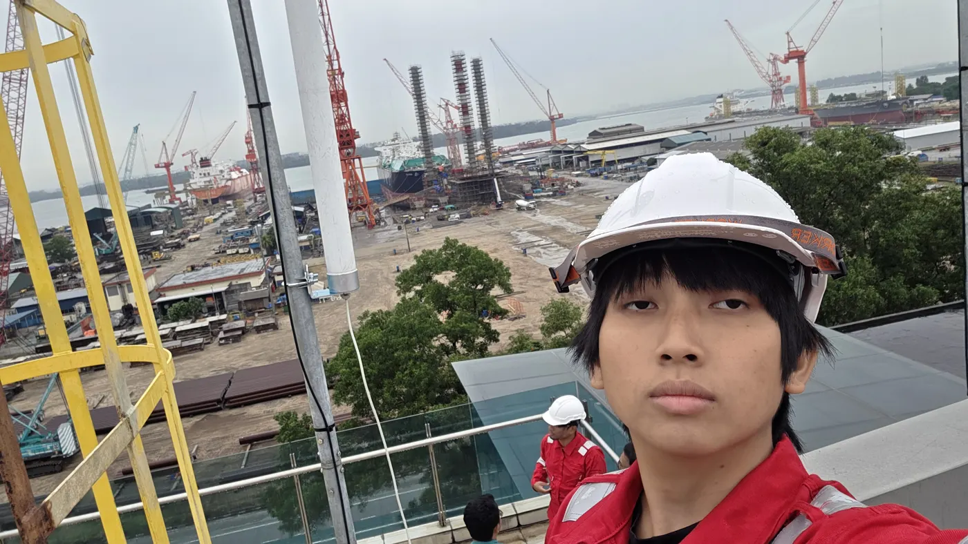 Zahin in a hard hat on a tower above the shipyard